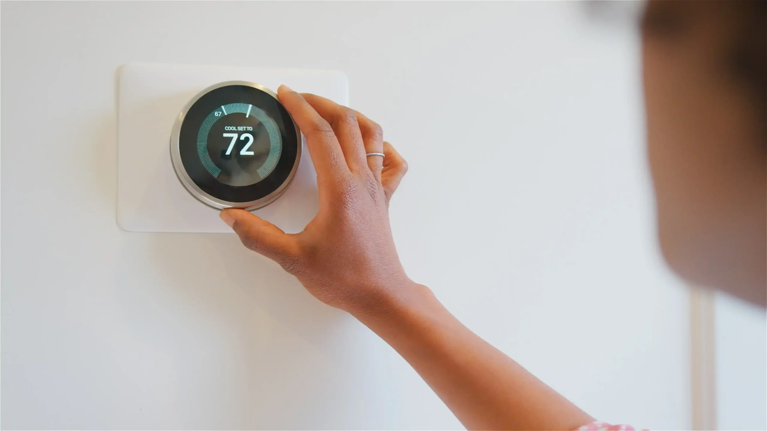 Close Up Of Woman Setting Digital Smart Heating Thermostat At Home